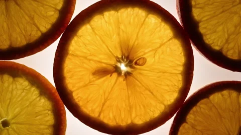 Backlit citrus slices rotating smoothly forming geometric abstract loop pattern Video stock 331259542