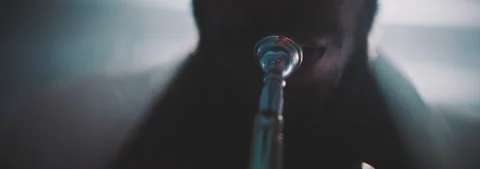 Backlit close up view of a men playing the trumpet in his house Stock Footage 202310415