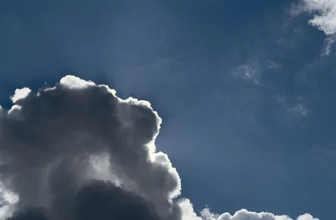 Backlit cloud against blue sky. Bright rim light around a dramatic cumulus 库存照片