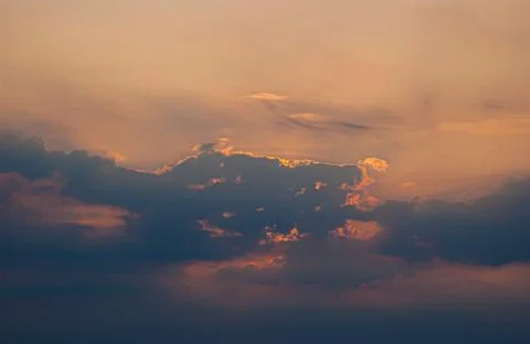 Backlit clouds during a vibrant and intensely orange sunset. Stock Photos