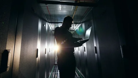 Backlit computer engineer is working in the server room Video stock 113359641