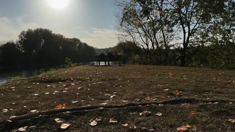 Backlit couple sitting on bench by river, low-angle ground view Stock-Footage 279434338