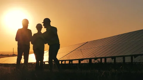 Backlit experts are passing by solar batteries and discussing them. Renewable Stock Footage 146522533