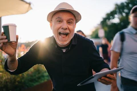 Backlit of joyful man user in straw hat rejoicing at city street Stock Photos