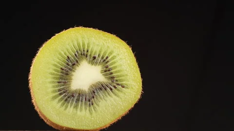 Backlit Kiwi Fruit Slice Glowing Isolated on Black Background Static Stock Footage 319910733