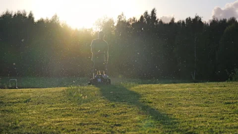 Backlit man cutting grass, wide shot Stock Footage 328617604