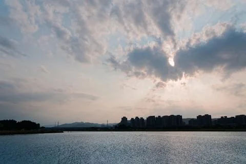 Backlit Riverfront Skyline Beneath Expansive Dramatic Afternoon Clouds 스톡 사진