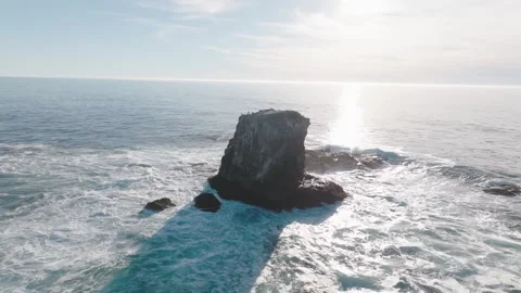 Backlit Sea Stack Aerial With Surf and Sun Glare on Ocean Stock Footage 333225455
