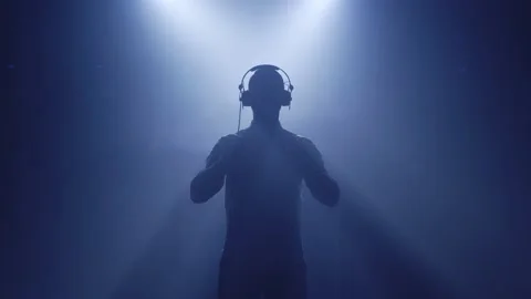 Backlit silhouette of dj man standing in dark nightclub disco, putting Stock Footage 145564344