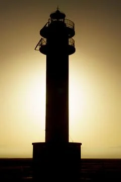 Backlit Silhouette of lighthouse during sunset Stock Photos