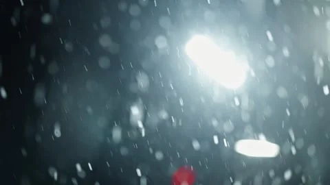 Backlit snowflakes drift through the dark night, captured in soft focus with Stock Footage 327063942