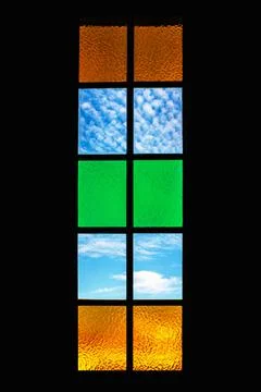 Backlit vertical rectangular window with stained colored glasses framed in black Stock Photos