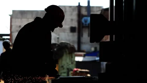 Backlit worker cleans a sheet of iron with a grinder Stock-Footage 167922873