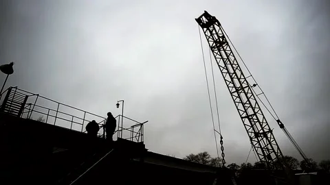 Backlit workers men work on a ramp at a manufacturing plant Stock Footage 144573954