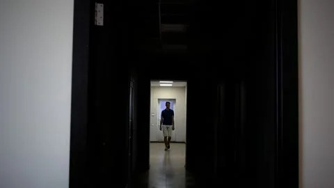 Backlit young man walks down the long corridor Stock-Footage 167922878