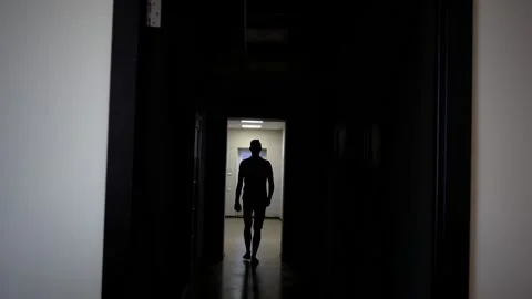 Backlit young man walks down the long corridor Stock-Footage 167922879