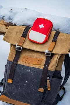 Backpack and first aid kit lying on snow during winter trip Stock Photos