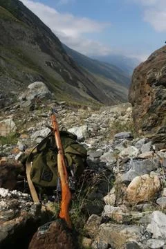 Backpack and rifle hunter on the rocks at the entrance Foto stock