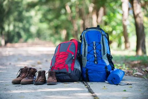 Backpack and shoes backpackers rest on the road while go hiking. Stock Photos