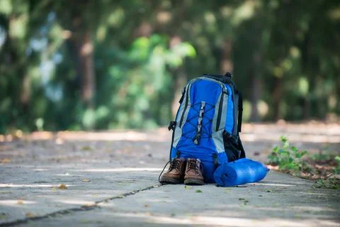 Backpack and shoes backpackers rest on the road while go hiking. Stock Photos