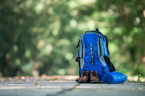 Backpack and shoes backpackers rest on the road while go hiking. Stock Photos