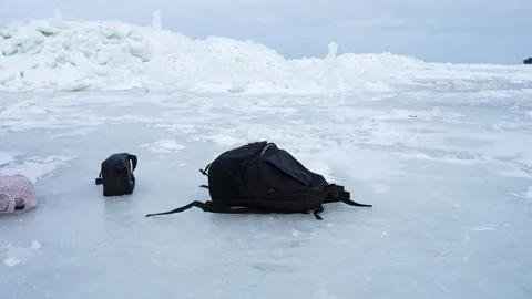 Backpack and small pouch abandoned on frozen sea ice near a jagged ice ridge Stock Footage 332096404