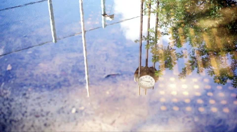 Backpack of the baseball stadium reflecting on the puddle and the clock of t Stock Footage 67626862