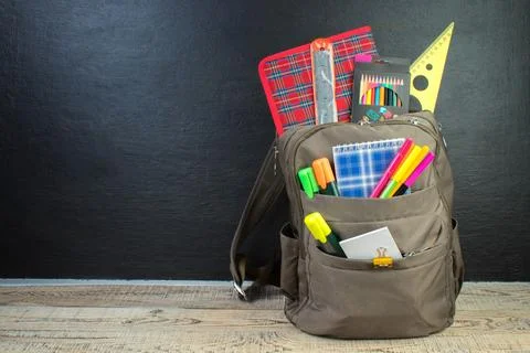 Backpack with different colorful stationery on table. Black background. Bac.. Stock Photos