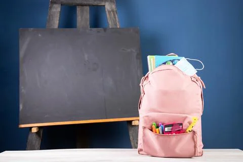 Backpack with different school stationery and medical mask. Coronavirus conce Stock-Fotos