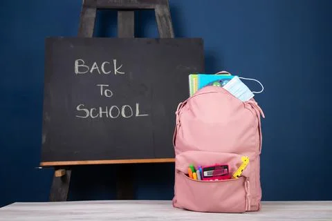Backpack with different school stationery and medical mask. Coronavirus conce Stock Photos