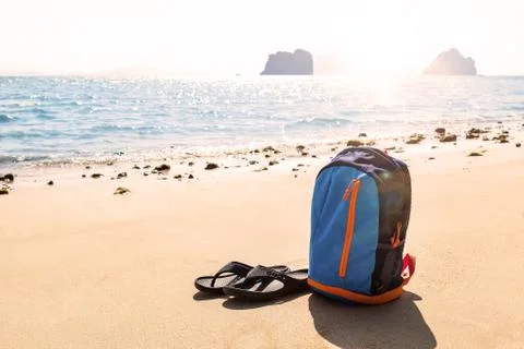 Backpack with flip-flops on beautiful sandy beach. Stock Photos