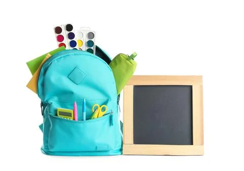 Backpack full of different school stationery and small blank chalkboard on wh Stock Photos