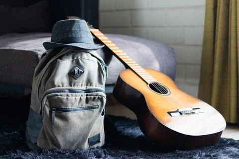 A backpack, a hat, and a guitar ready to travel Stock Photos