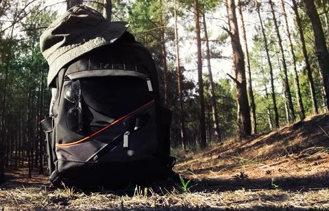 Backpack with hat, glasses and flashlight laying on forest ground. Stock Photos