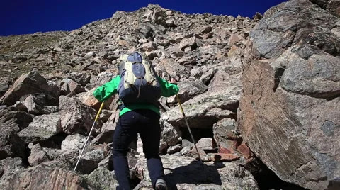 Backpack hiker climbs rock field up mountain Stock Footage 50960253