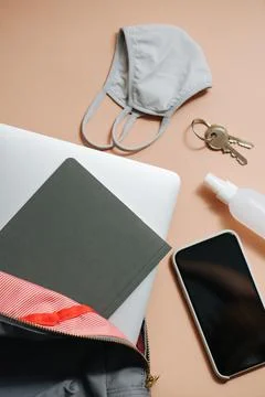 Backpack with laptop and notebook in it. Other everyday items on a peach surface Stock Photos