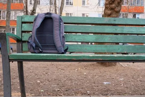 Backpack left on a green park bench Stock Photos