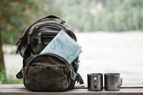Backpack with maps and two mugs. Stock Photos