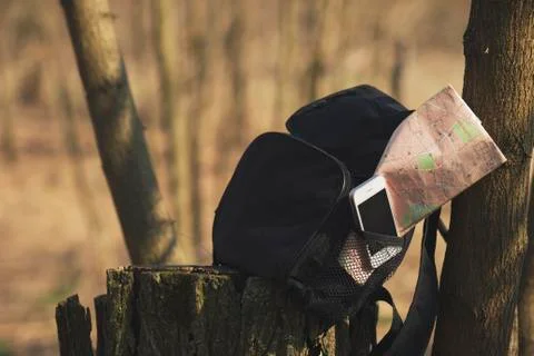 Backpack with phone and map in the pocket on the stump Stock Photos