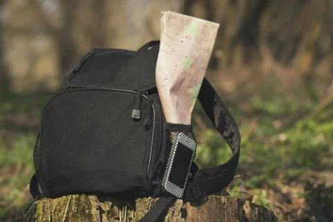 Backpack with phone and map in the pocket on the stump Stock Photos