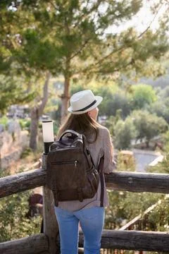 Backpacker admires forest landscape while leaning against wooden fence. Woman Stock Photos