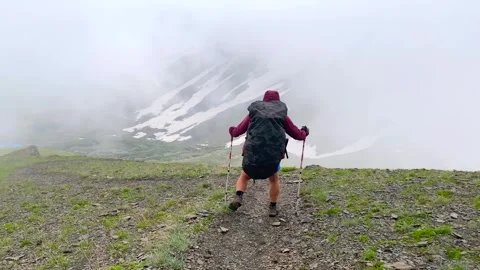 A backpacker advances through dense fog across the rocky Chaukhi Pass Видео 340388721