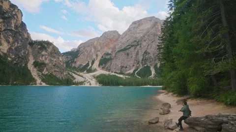 Backpacker approaching rock viewpoint at Lago di Braies Dolomites Italy Stock Footage 320103599