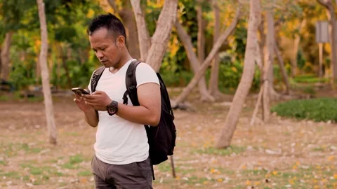 Backpacker asian man using mobile phone at the outdoor park. Stock Footage 301189169