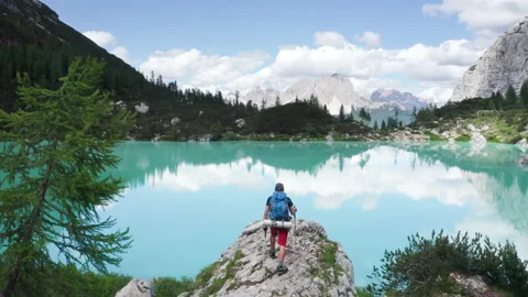 Backpacker with backpack walking up the cliff to enjoy turquoise Lago di Sorapis Stock Footage 203837364
