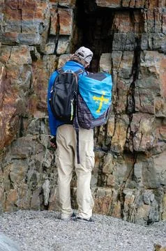 Backpacker with blue flag exploring rocky cliff outdoors, rear view Foto stock