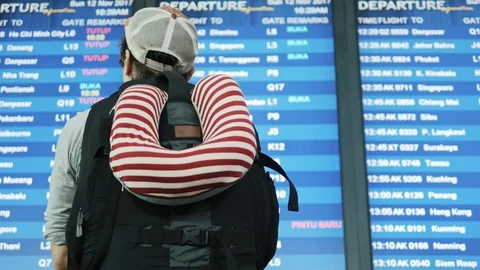 Backpacker checking flight information on digital schedule display in iairport Stock Footage 88246569