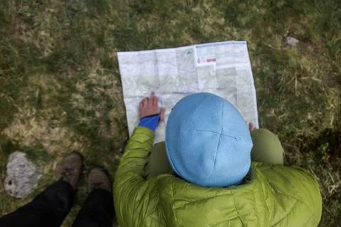 Backpacker consulting navigation map in natural setting. Hiker wearing blue.. Stock Photos