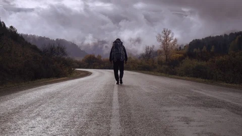 Backpacker on empty remote road looking around Stock Footage 102531778