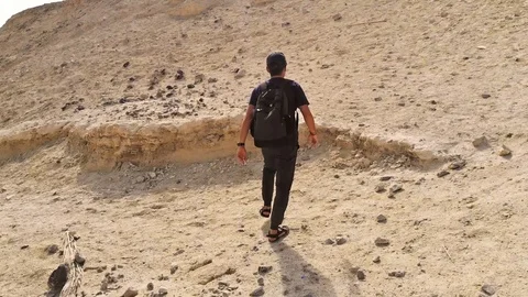 Backpacker goes to the mountain on the sand and opens a beautiful view from the Stock Footage 100204527